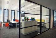 Web development team office viewed from the corridor through open door and soundproof glass wall.